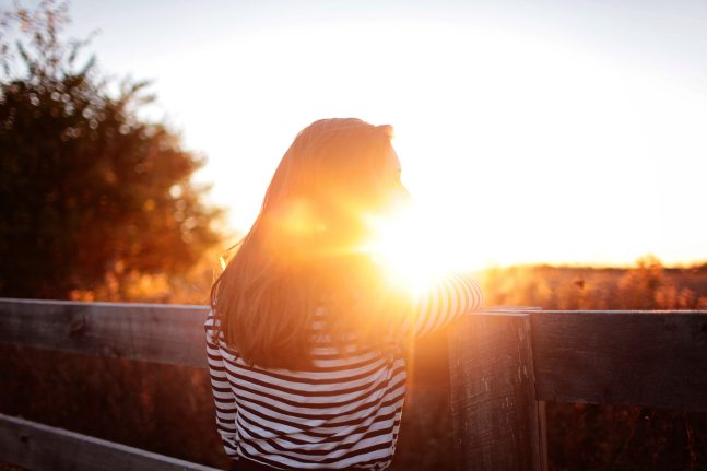 rear-view-of-woman-standing-in-balcony-during-sunset-325520